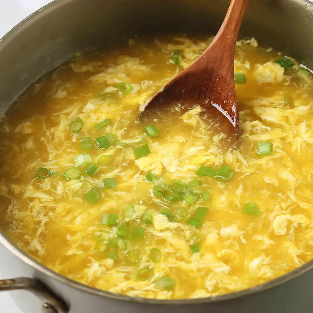 Bowl of egg drop soup topped with scallion greens