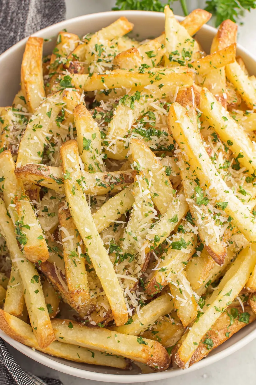 Hands tossing fries with parmesan and garlic