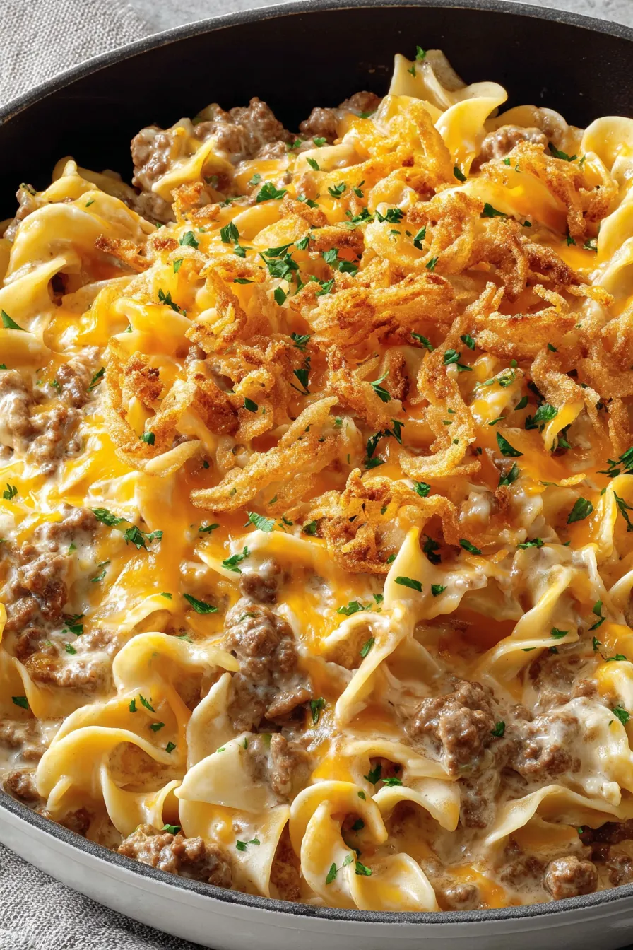 Spoon lifting a cheesy portion with crispy onion topping