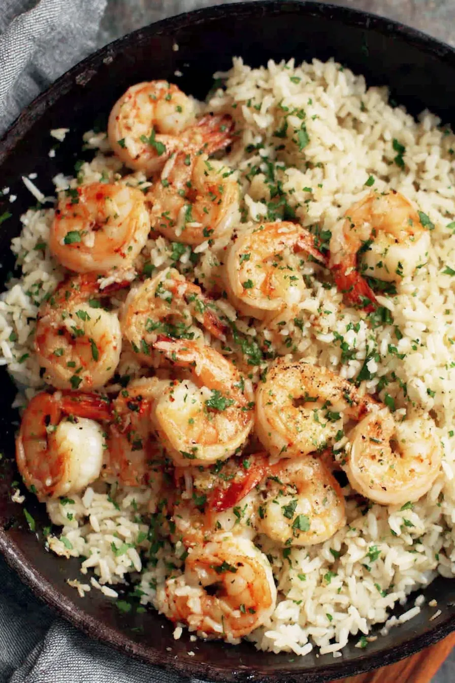 Plated garlic butter shrimp over rice garnished with parsley