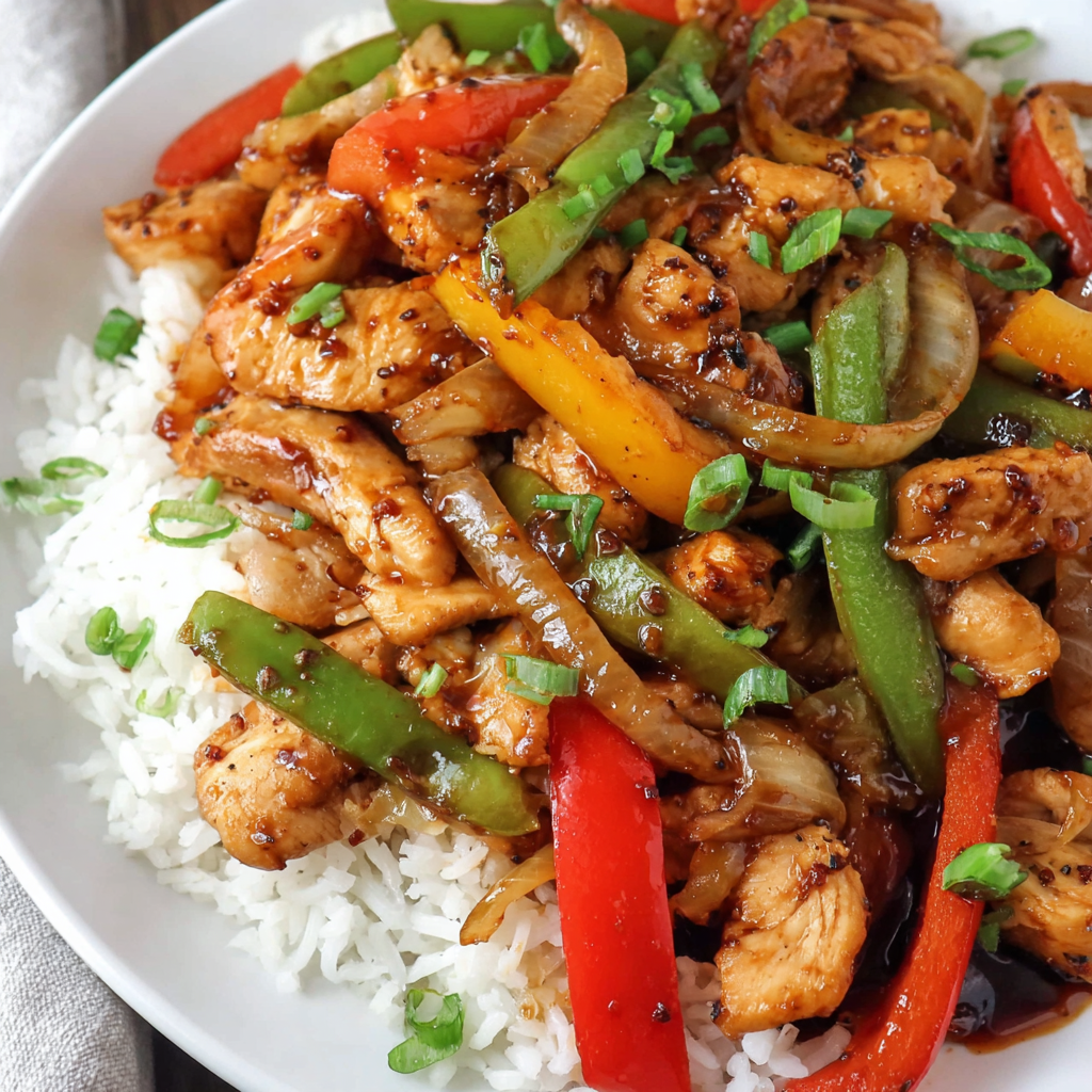 Serving bowl of sweet and spicy chicken stir fry with rice on the side