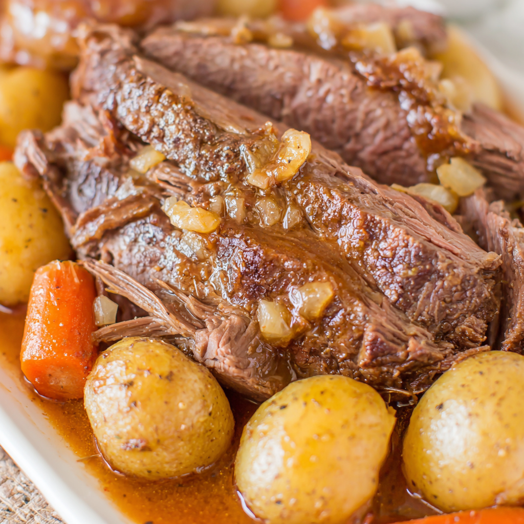 Sliced top round roast plated with carrots and potatoes