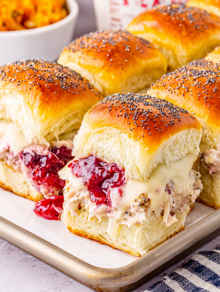 Sliced turkey and Swiss cheese arranged on Hawaiian roll bottoms in a baking dish