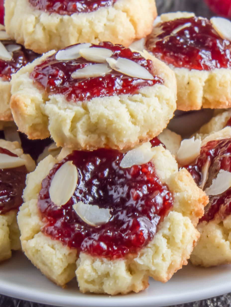 Close-up of a single thumbprint cookie with jam and a drizzle of glaze