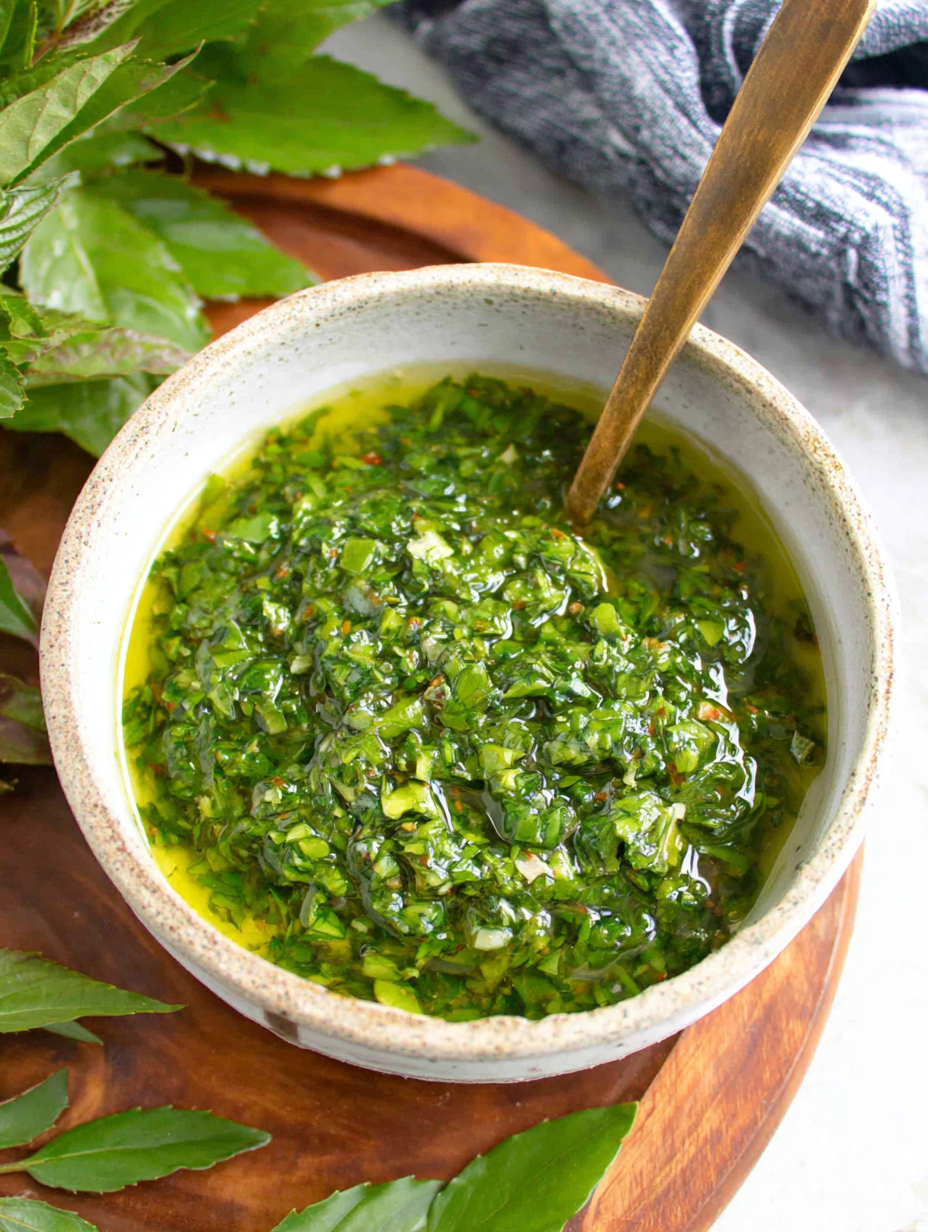 Bright chimichurri sauce in a bowl with herbs