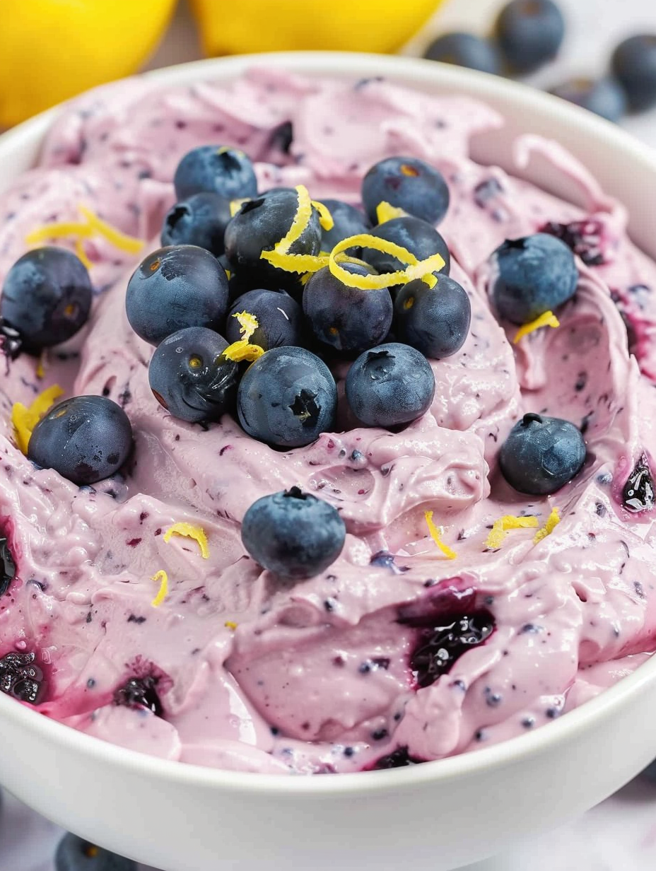 Blueberry fluff in a glass serving bowl topped with fresh blueberries