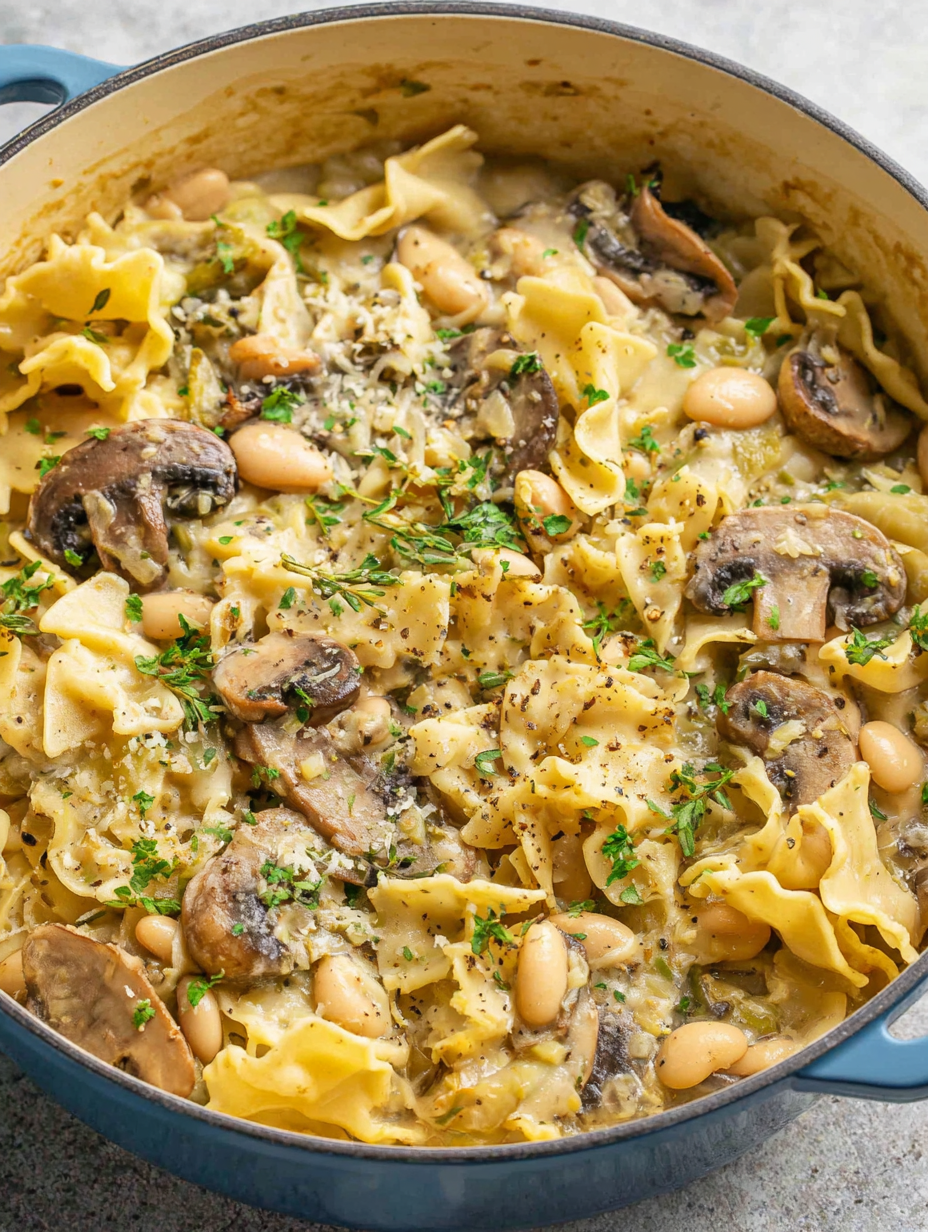 One pot pasta simmering in a large pot with mushrooms and broken lasagna noodles