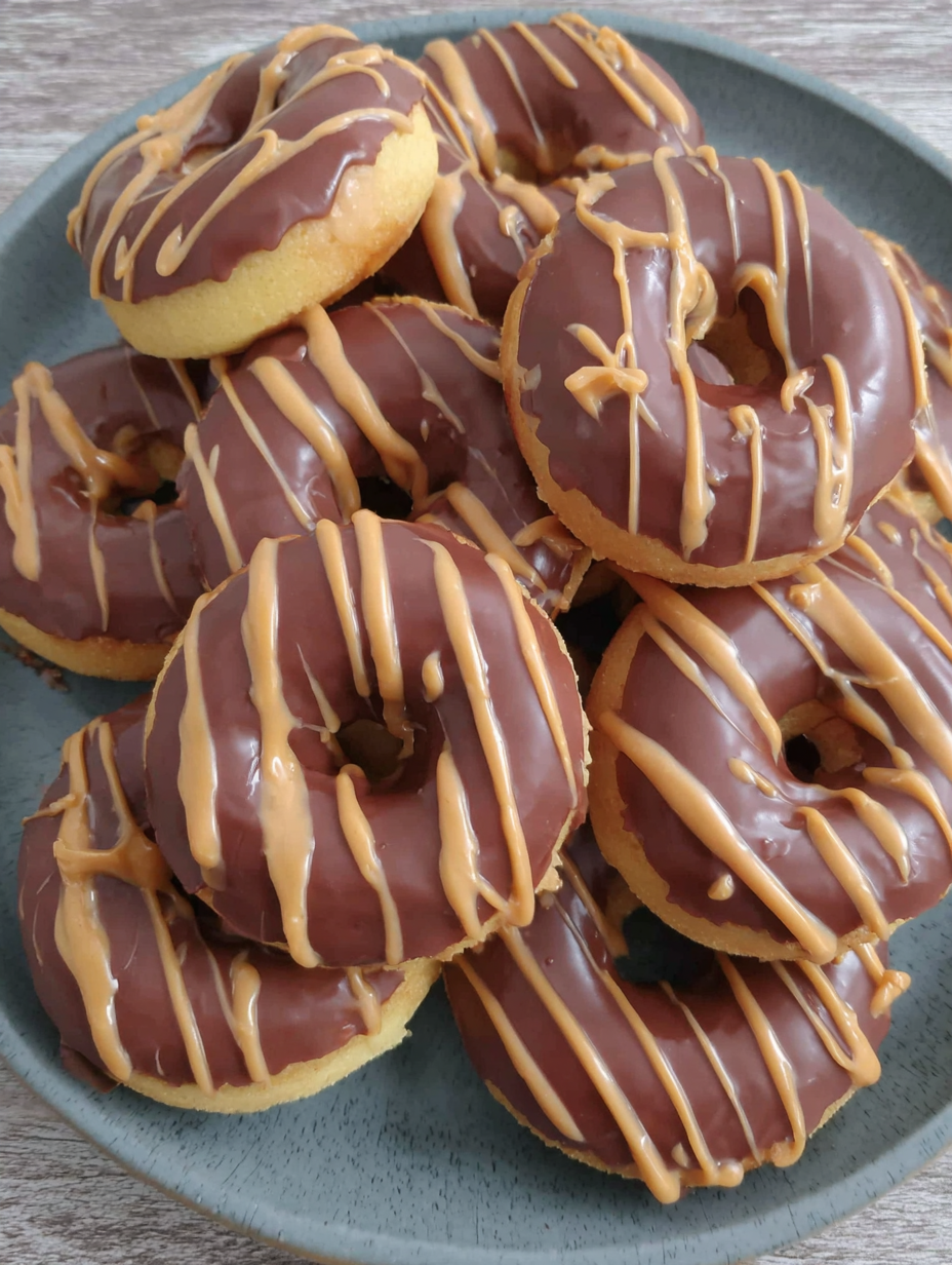 Peanut butter drizzling over chocolate glazed donuts
