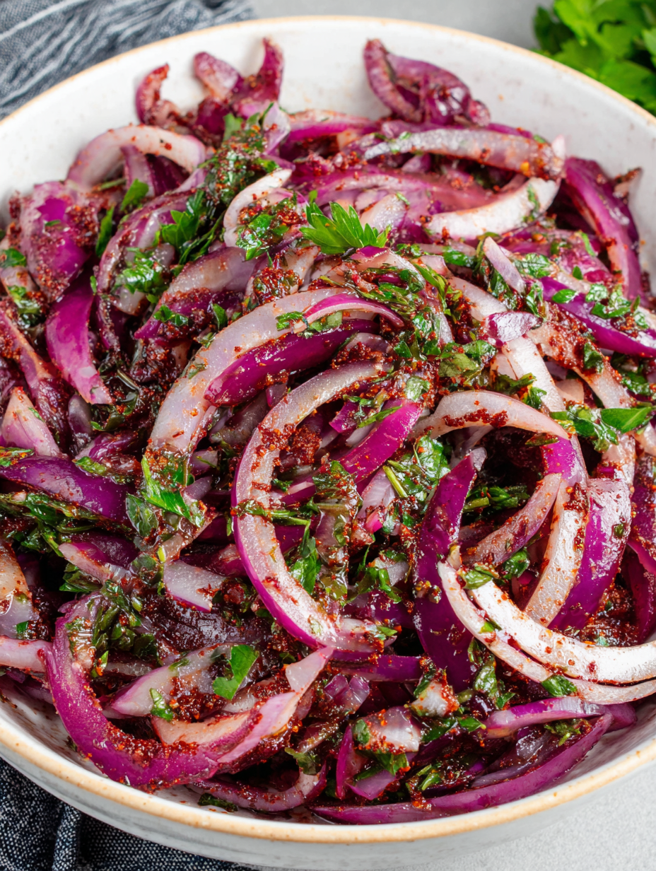 A bowl of marinated sumac onions next to flatbread and grilled skewers