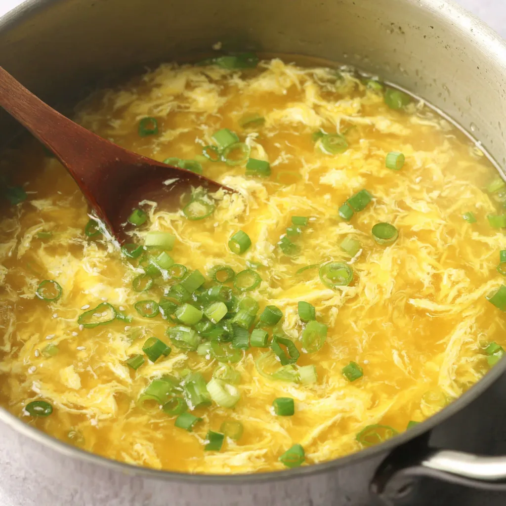 Close-up of egg drop soup showing delicate egg flowers and scallion garnish