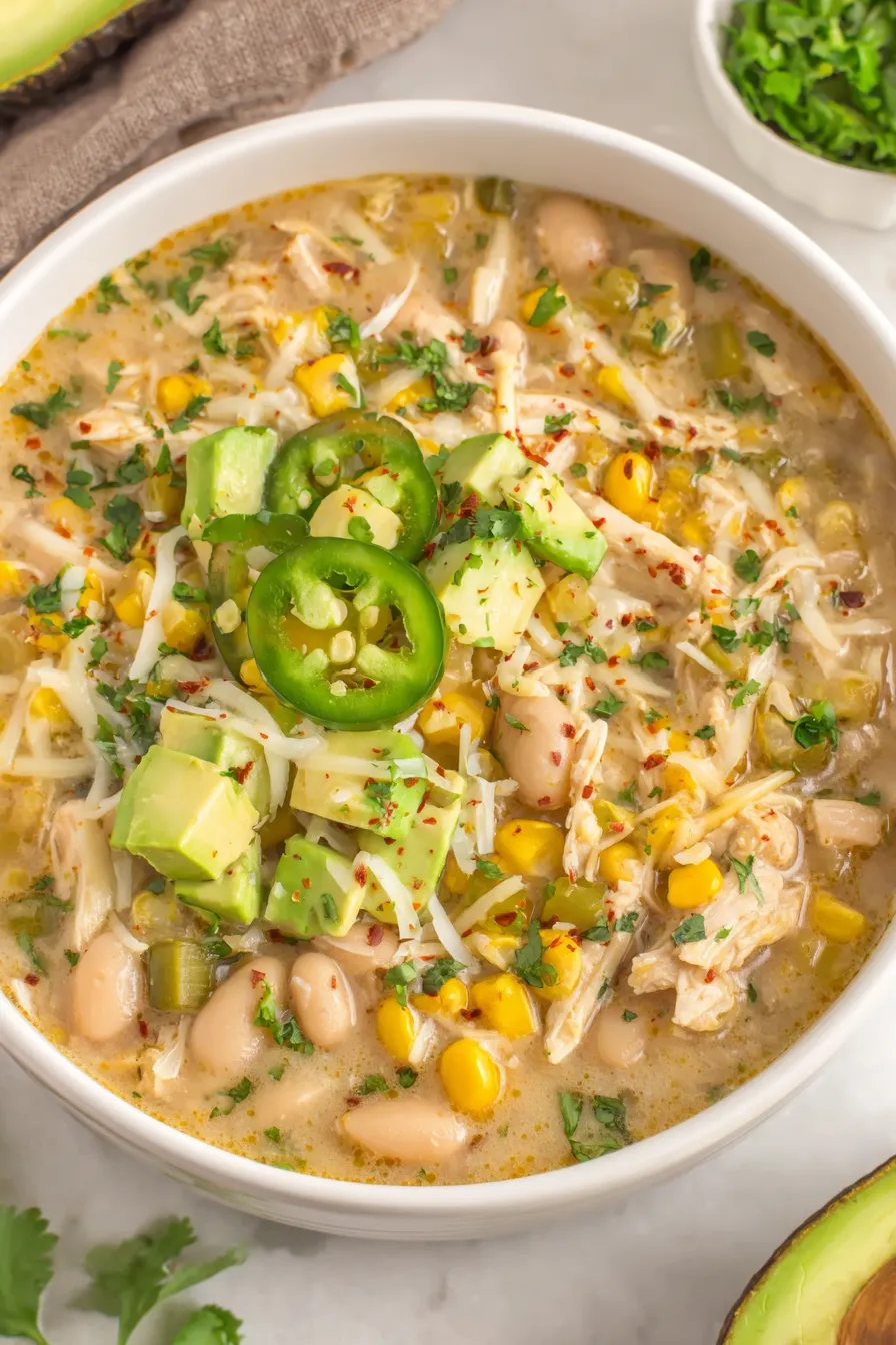 Bowl of white bean chili garnished with cilantro and avocado