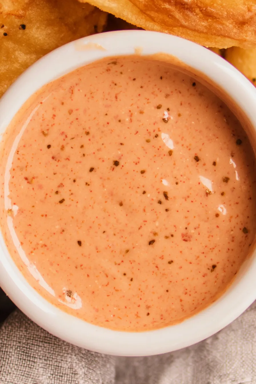 Creamy fry sauce in a small bowl beside a plate of fries