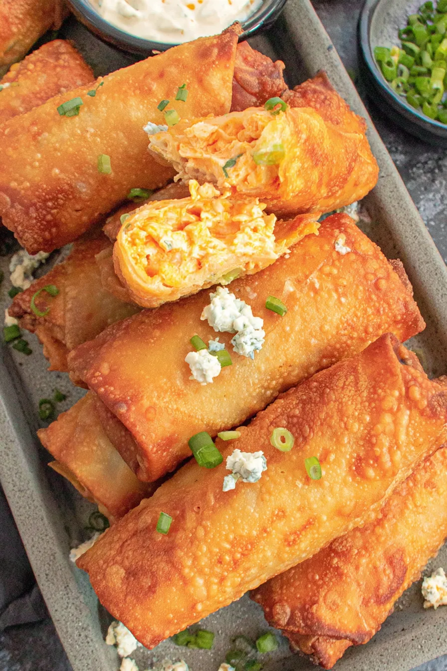 Stack of prepared egg roll wrappers and bowls of filling