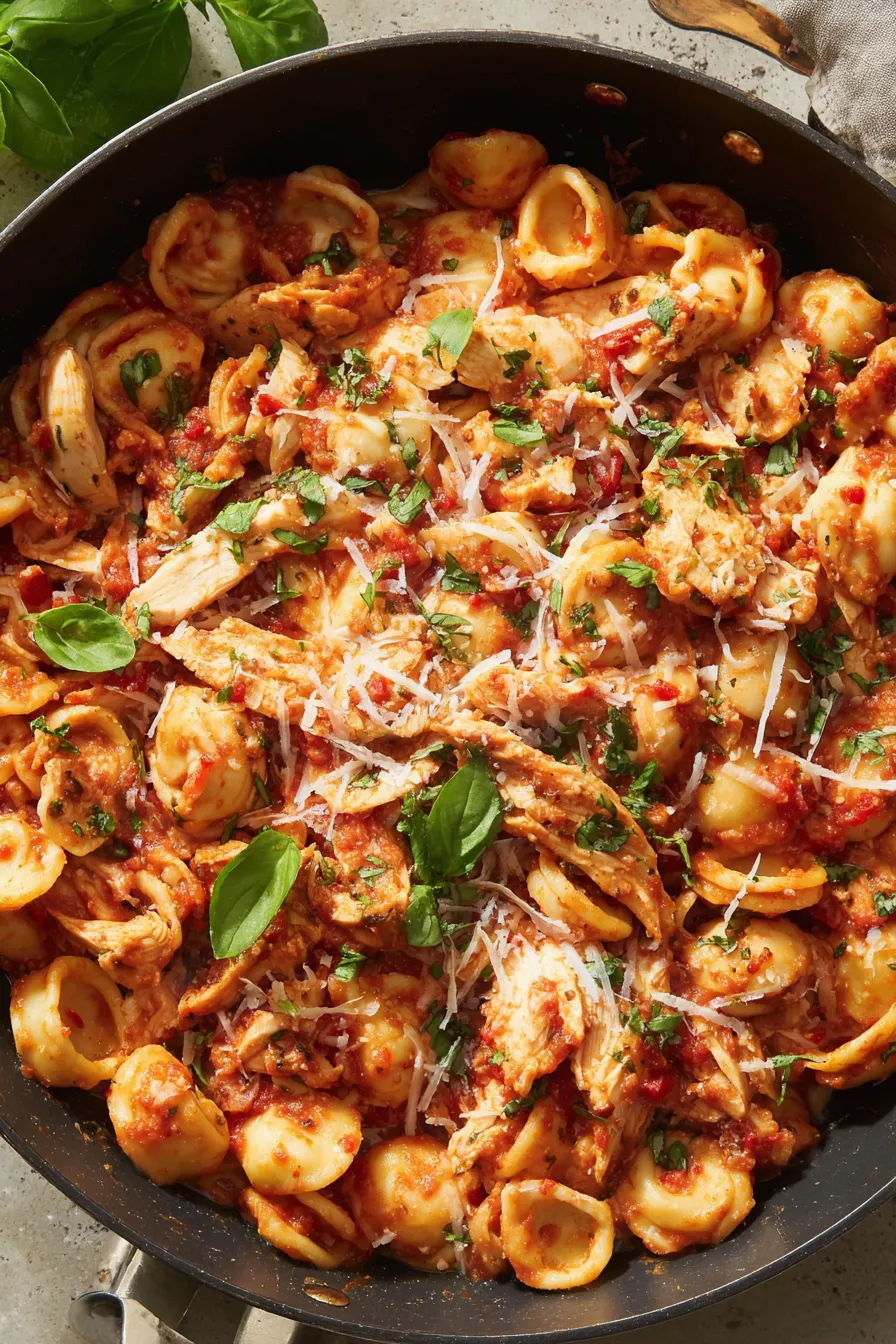 Served bowl of spicy chicken pasta garnished with basil