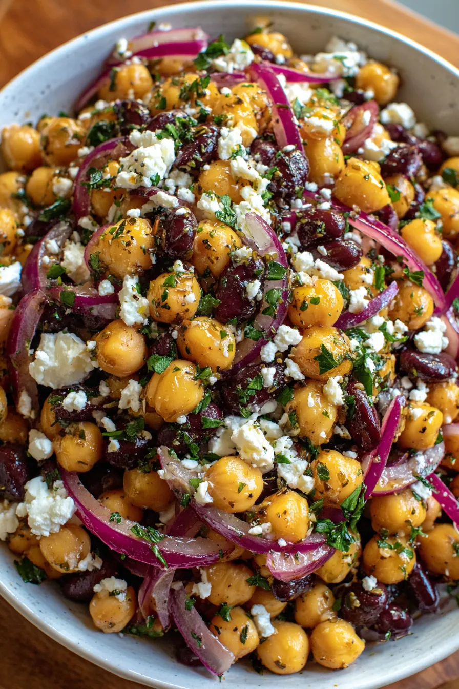 Chickpeas and black beans tossed with herbs in a glass bowl
