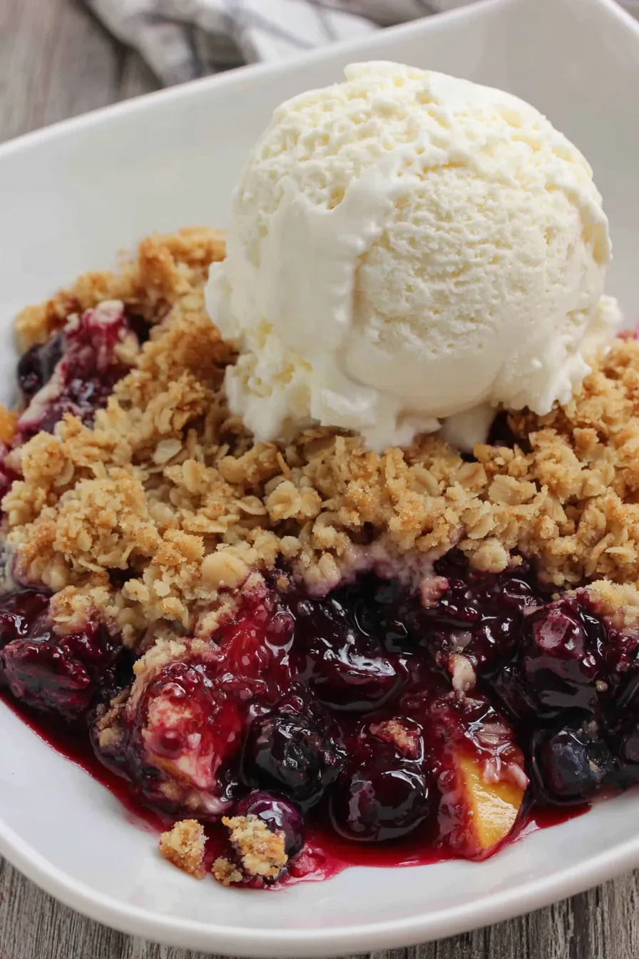 Blueberry peach crisp in a baking dish, steam rising
