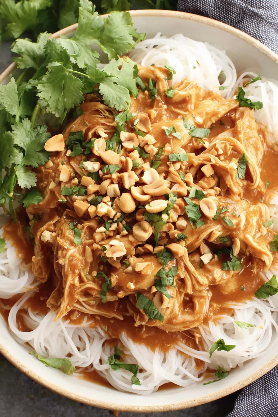 Slow cooker Thai peanut chicken in a bowl topped with chopped peanuts and cilantro