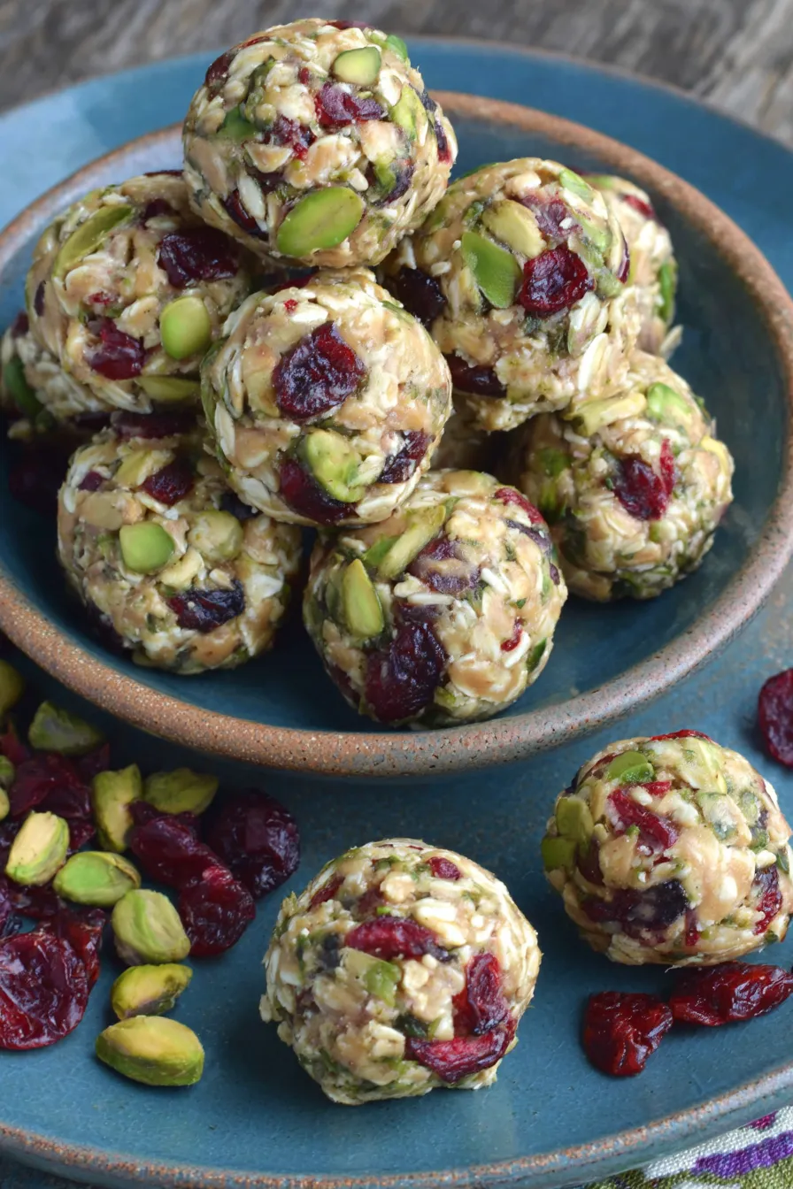 Close-up of a cranberry and pistachio energy ball with pistachios around
