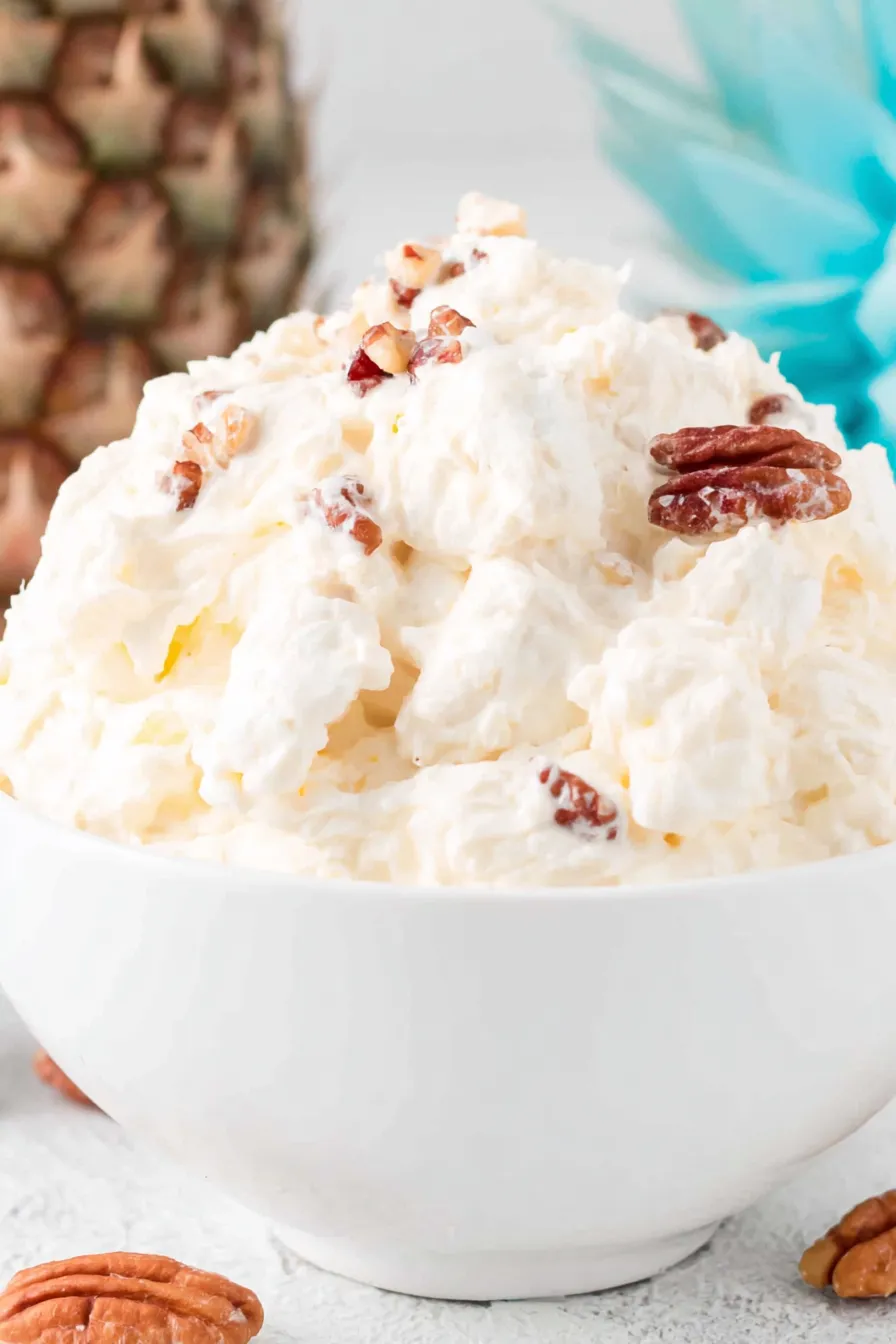 Piña Colada Fluff in a bowl with toasted coconut and walnuts
