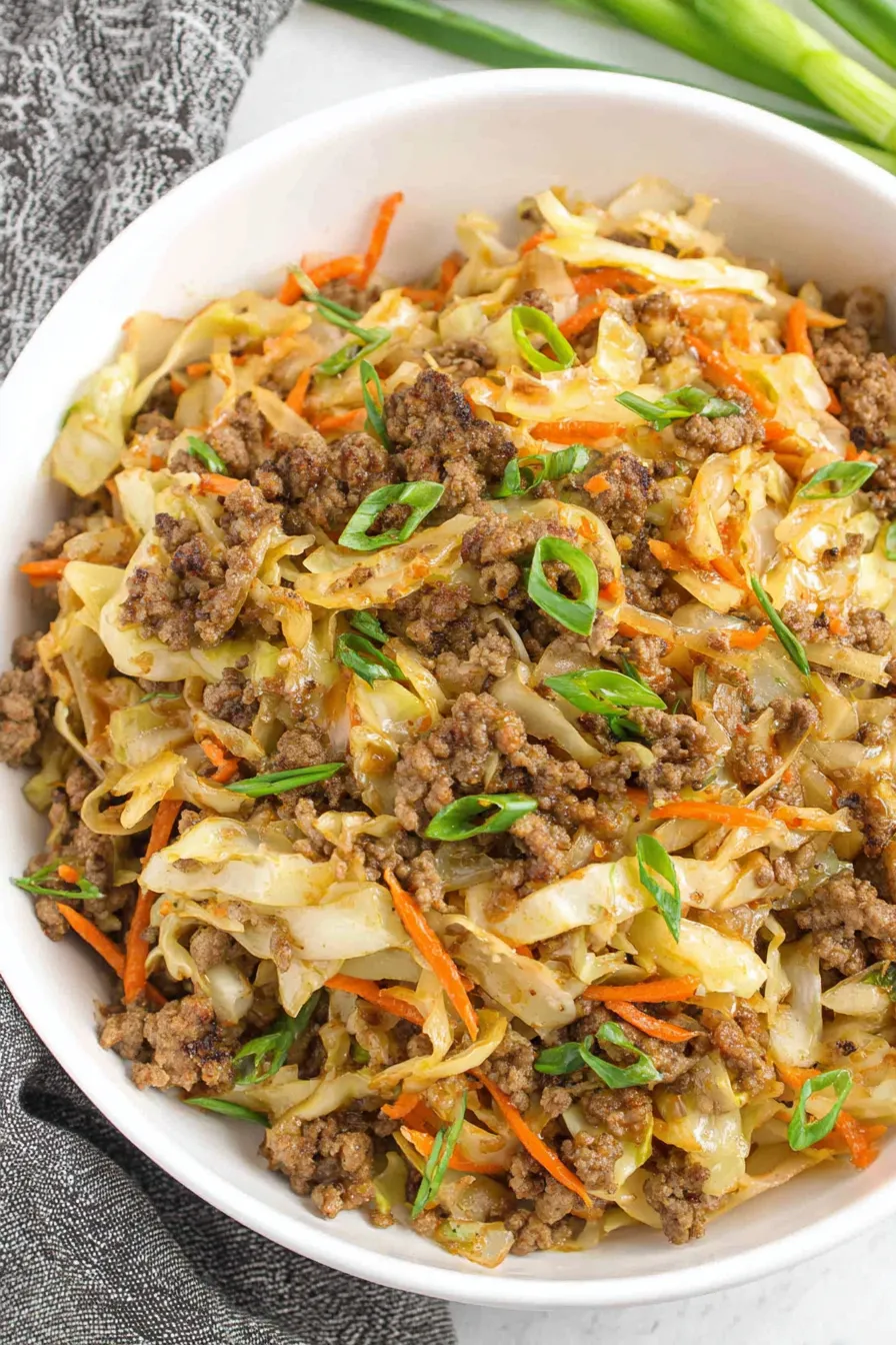 Ground beef and coleslaw mix cooking in a skillet