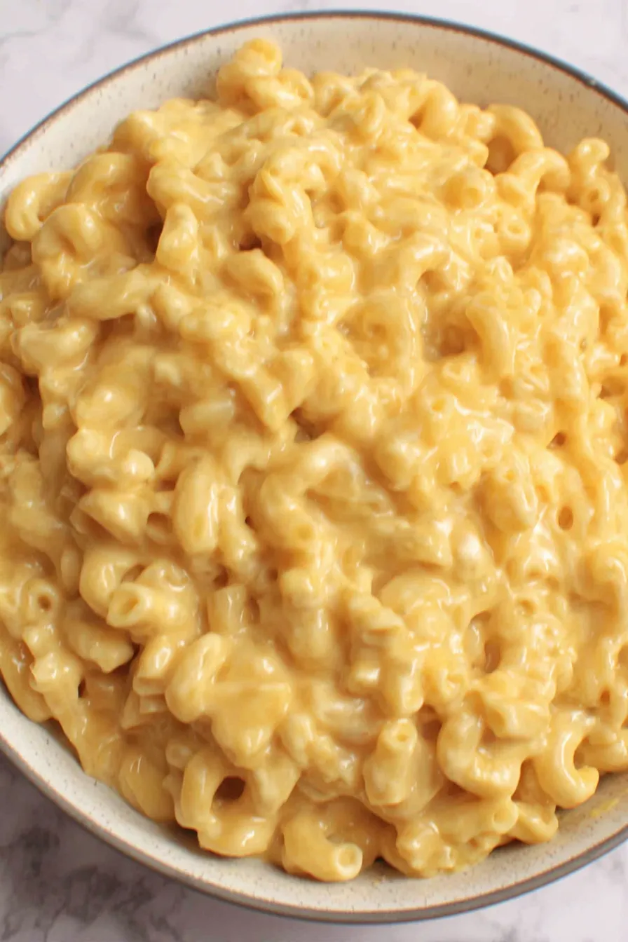 Creamy mac and cheese in a white dish with melted cheddar