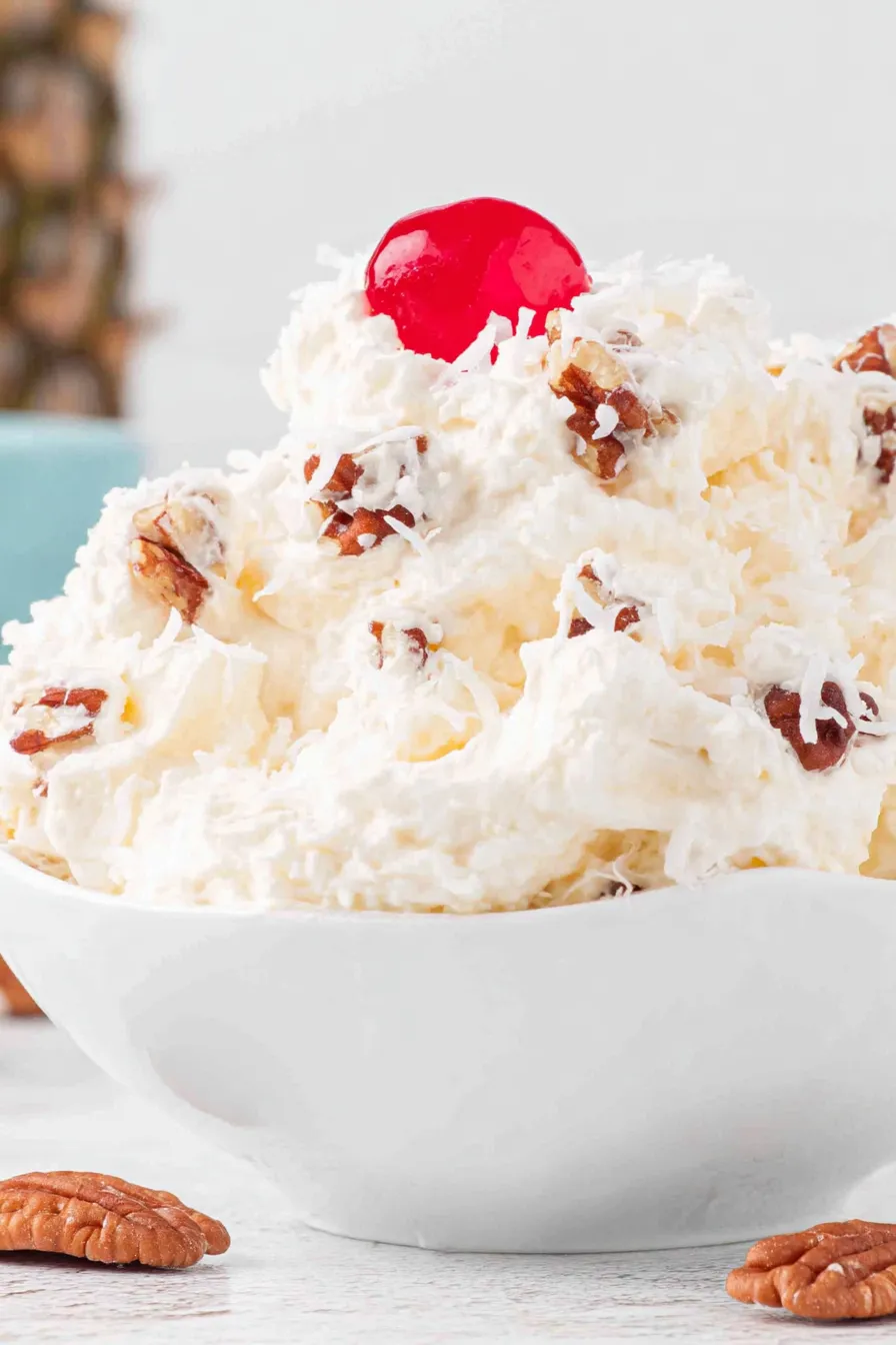 Mixed Piña Colada Fluff in a bowl with coconut and walnuts