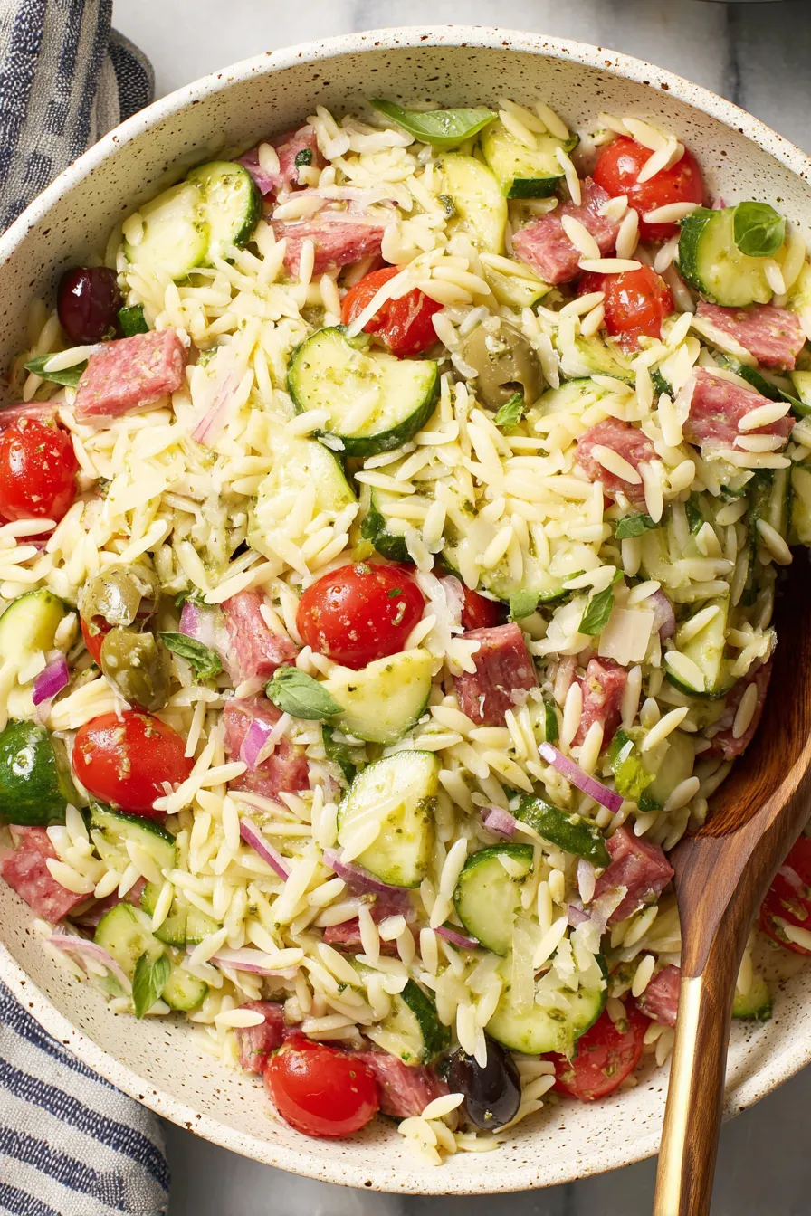 Close-up of orzo salad ingredients being mixed