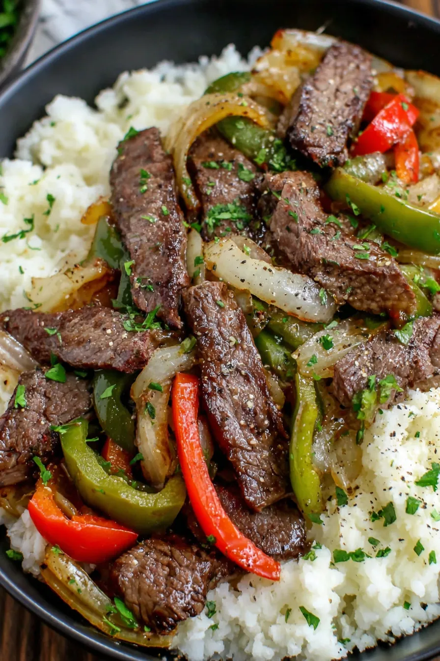 Close-up of melted cheese on top of steak and peppers