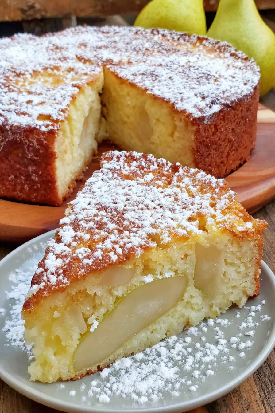 Pear ricotta cake on a wire rack with powdered sugar