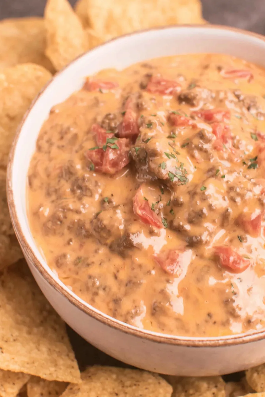 Slow cooker queso dip in a pot, creamy with chips on the side