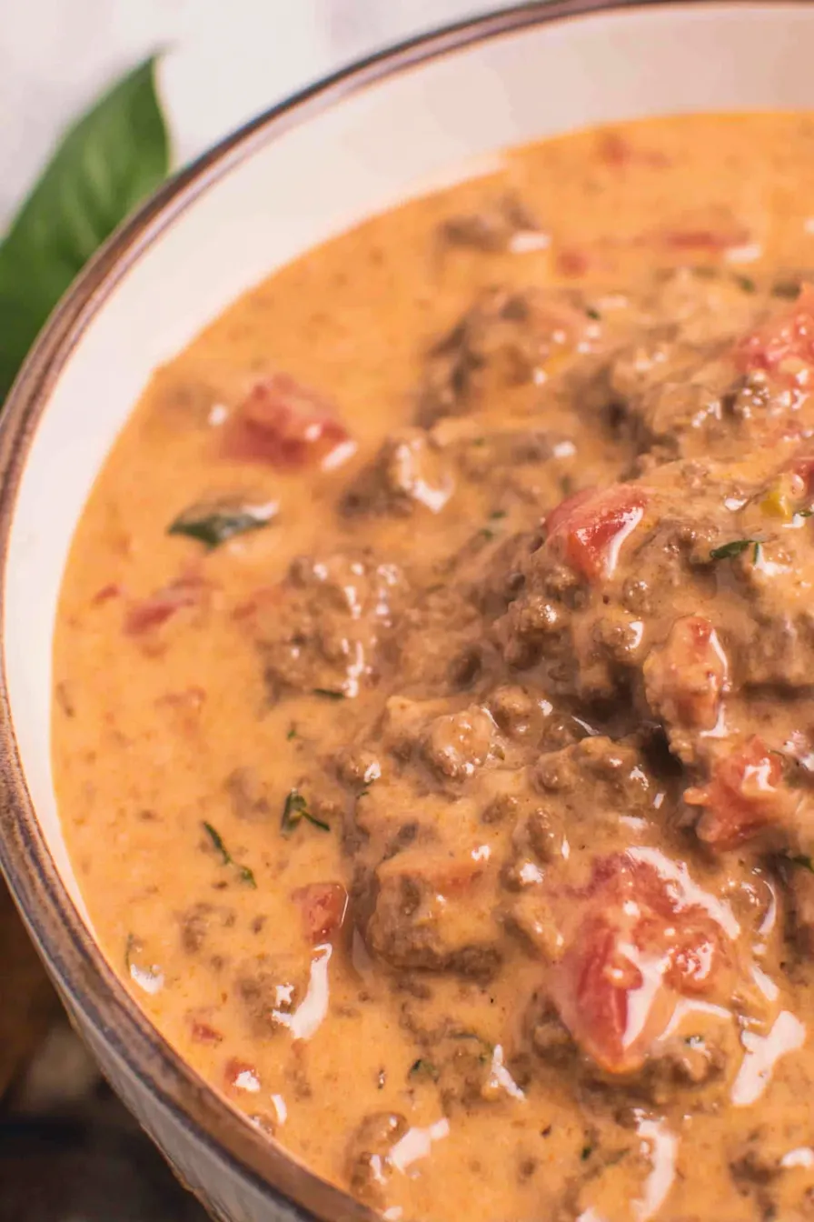 Close-up of creamy queso with chunks of beef and tomatoes