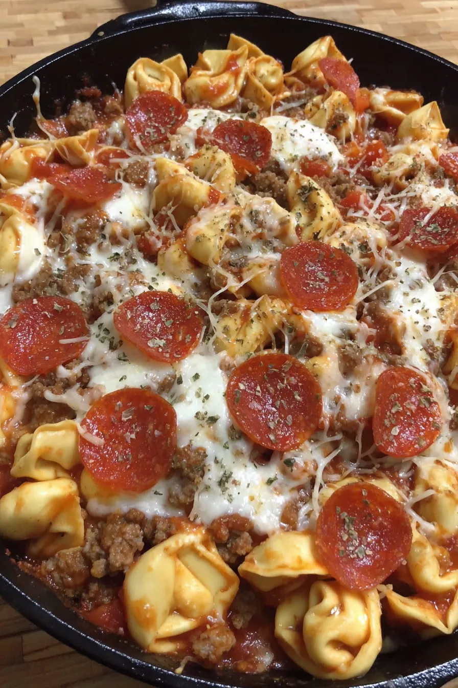 Serving spoon lifting cheesy tortellini from skillet