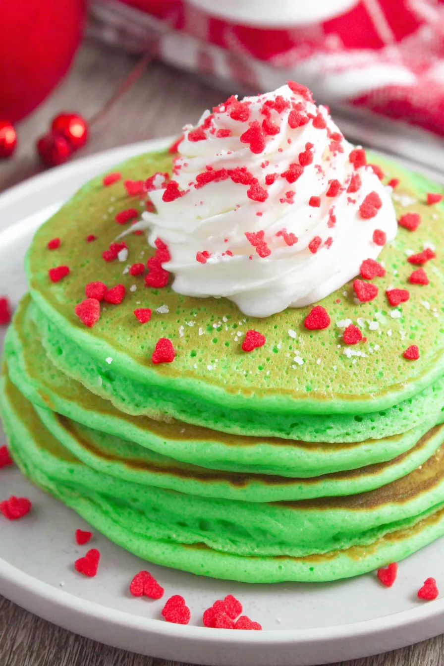 Close up of green whipped cream being piped onto a pancake