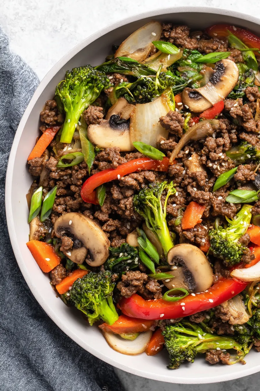Finished ground beef stir fry plated with rice and garnishes