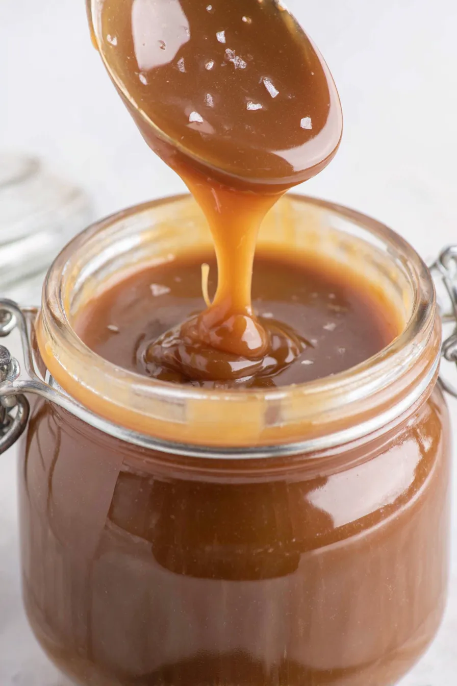 Small jar of toffee sauce beside a spoon