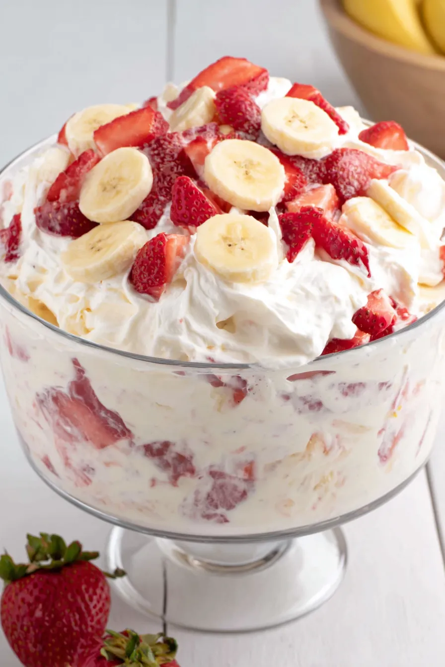Spoon scooping a creamy portion showing fresh strawberries and banana slices